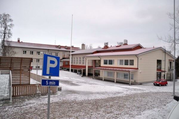 skolhus med ljus rappning och lite snö framför