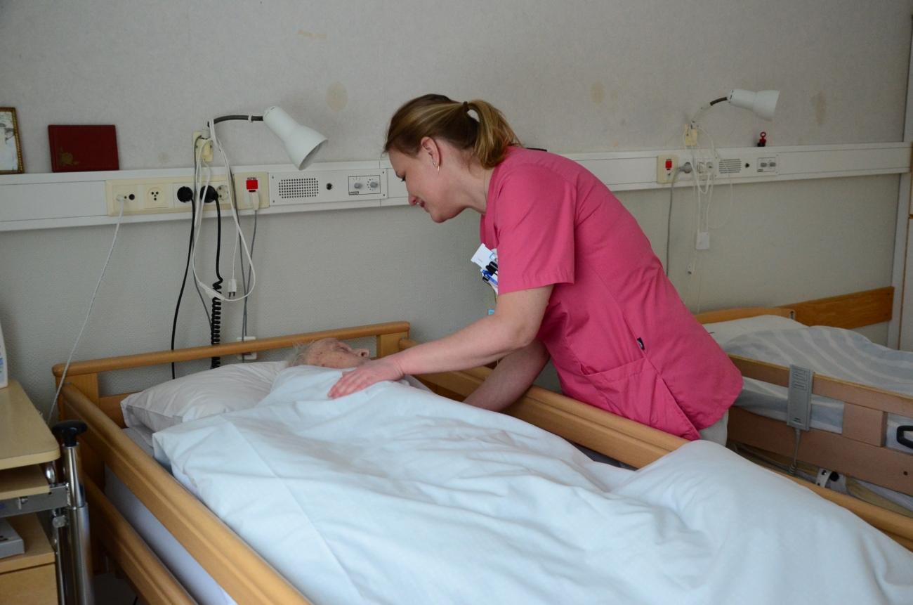 Sköterska böjer sig ner och talar med en patient