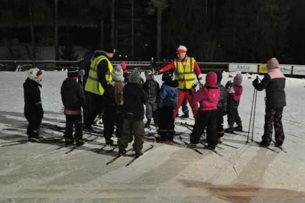 en grupp med barn och en ledare på skidor