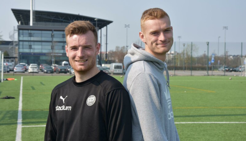 Två fotbollsspelare med ryggarna mot varandra.