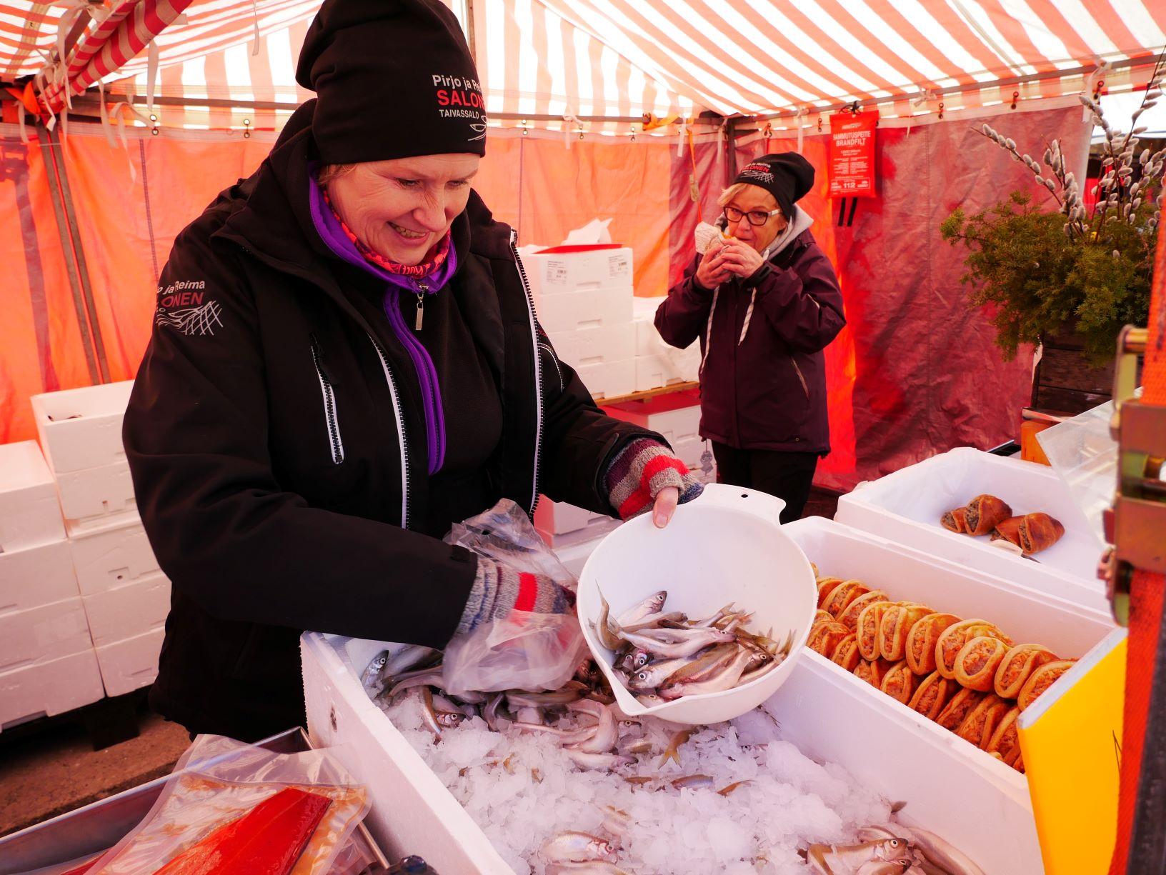 Kvinna med en låda fisk framför sig.