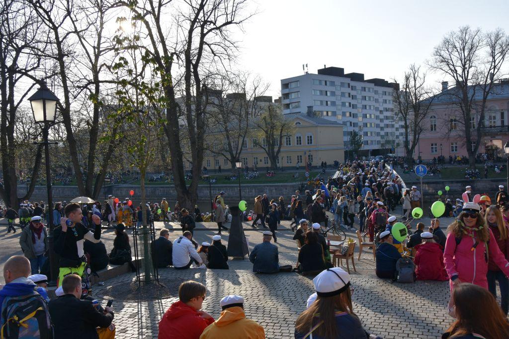 Stora mängder människor rör sig över Biblioteksbron och längs åstranden i Åbo.