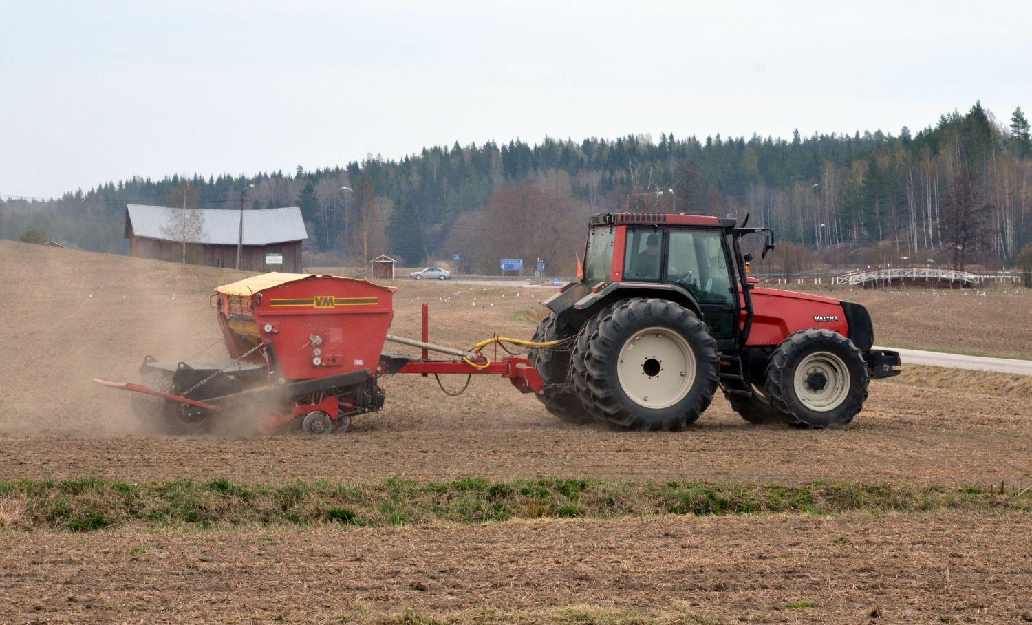 Traktor och såmaskin på dammig åker