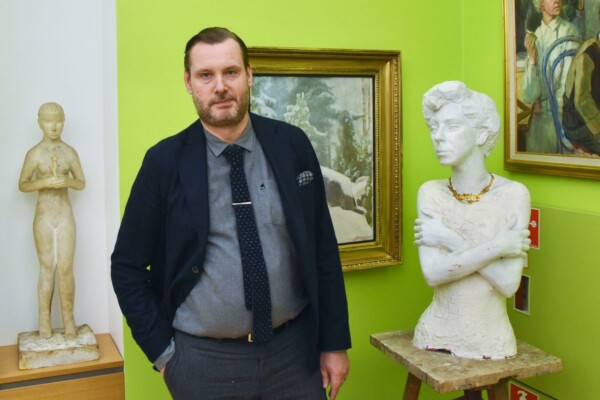 Man med två skulpturer i bakgrunden.