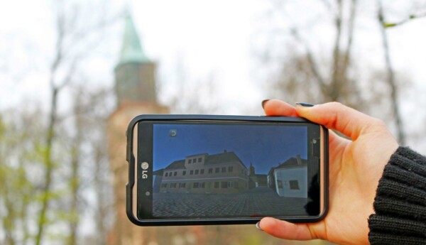 Mobiltelefon håls upp, kyrka i bakgrunden