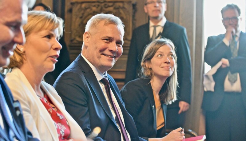 Två leende kvinnor och en man.
