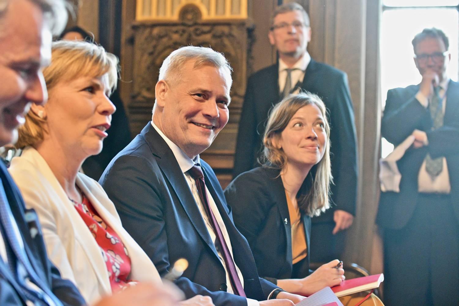 Två leende kvinnor och en man.