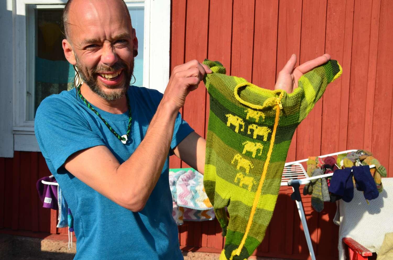 Skrattande man håller upp en babyoverall.