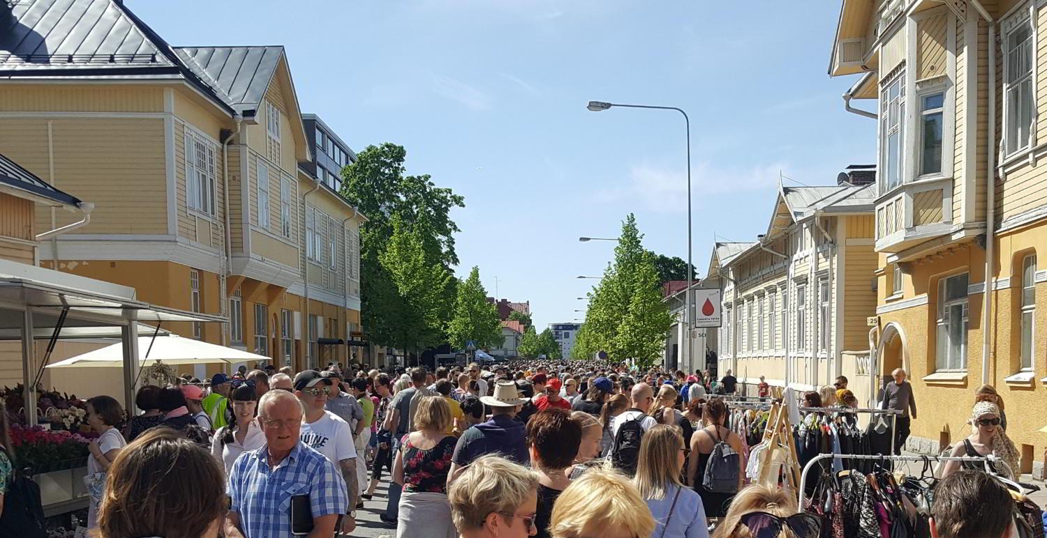 Mycket människor på en gata med trähus.