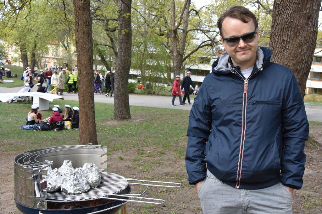En man står vid en grill i en park.