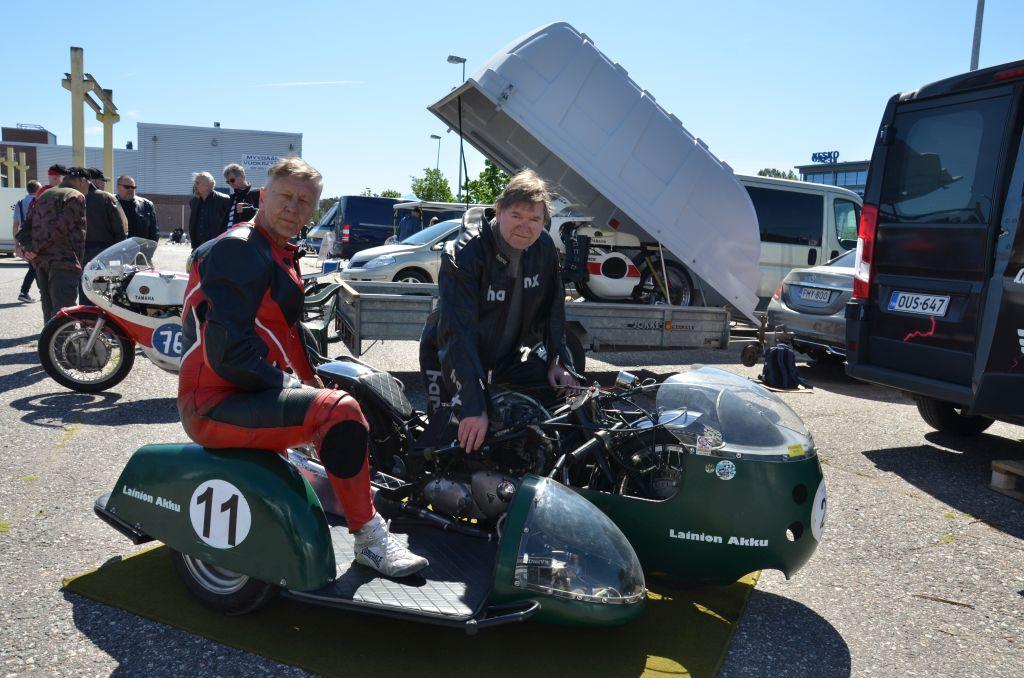 Två män sitter på en gammal grön motorcykel med sidovagn.