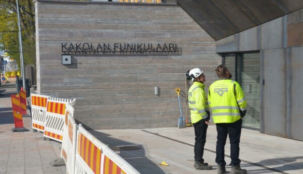 Två män i arbetskläder framför en byggnad