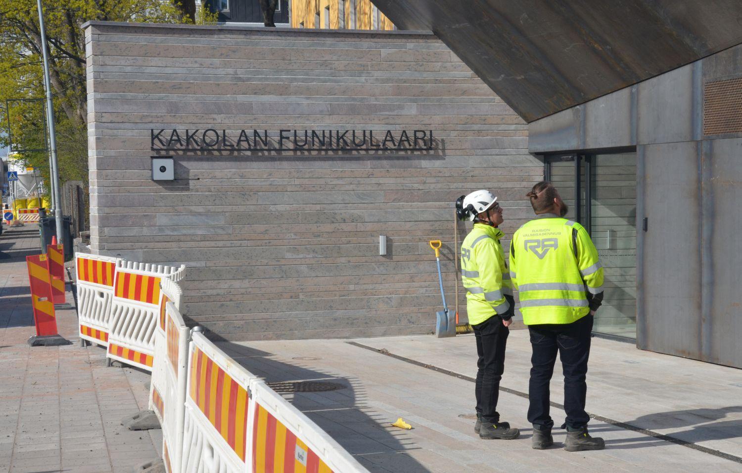 Två män i arbetskläder framför en byggnad