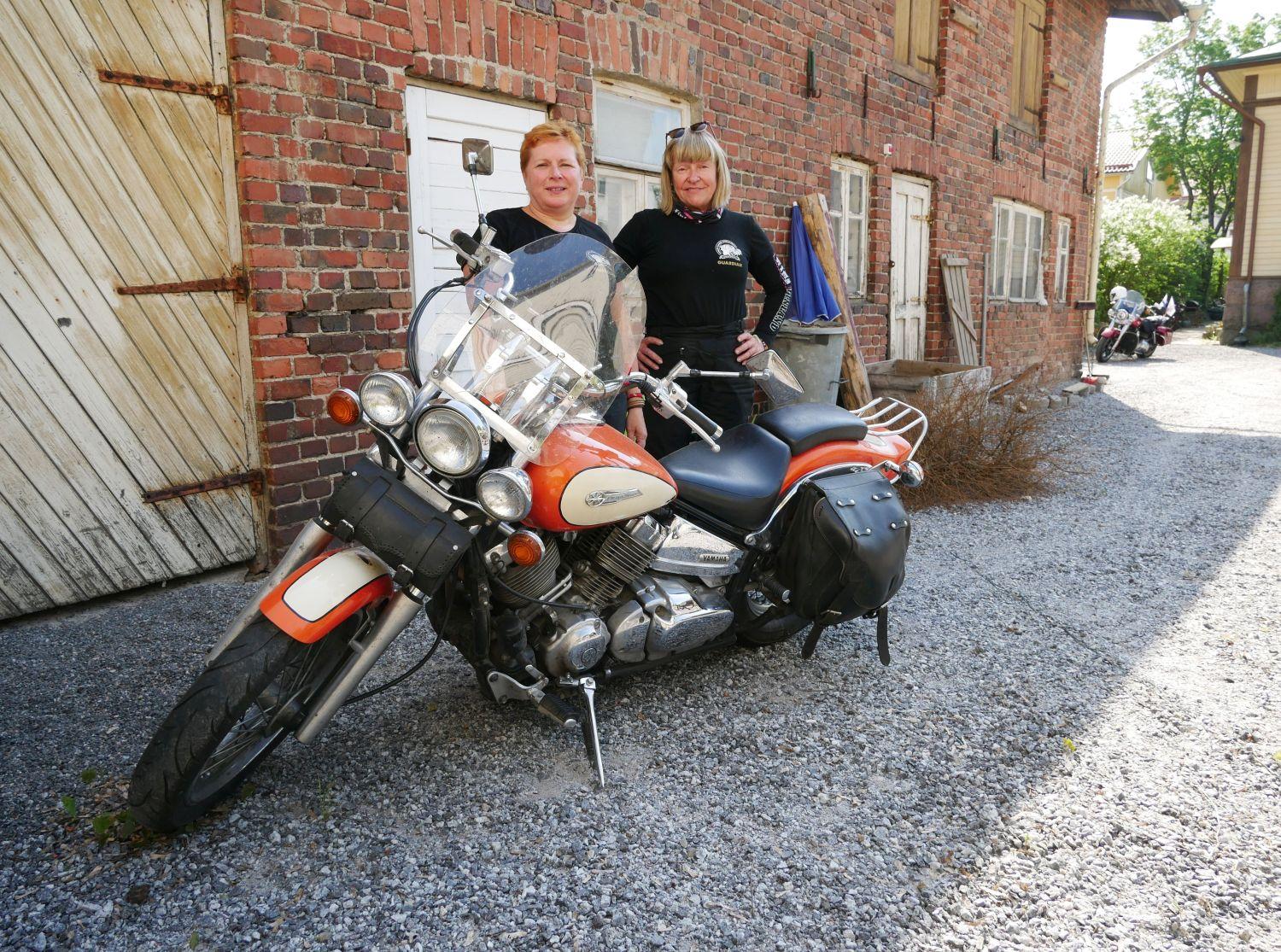 Två kvinnor står vid en motorcykel