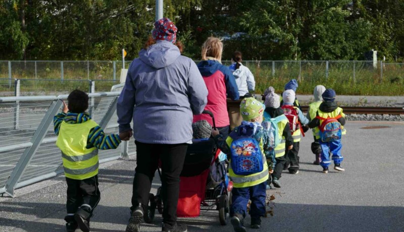 Dagisbarn med småbarnspedagoger ute på promenad.
