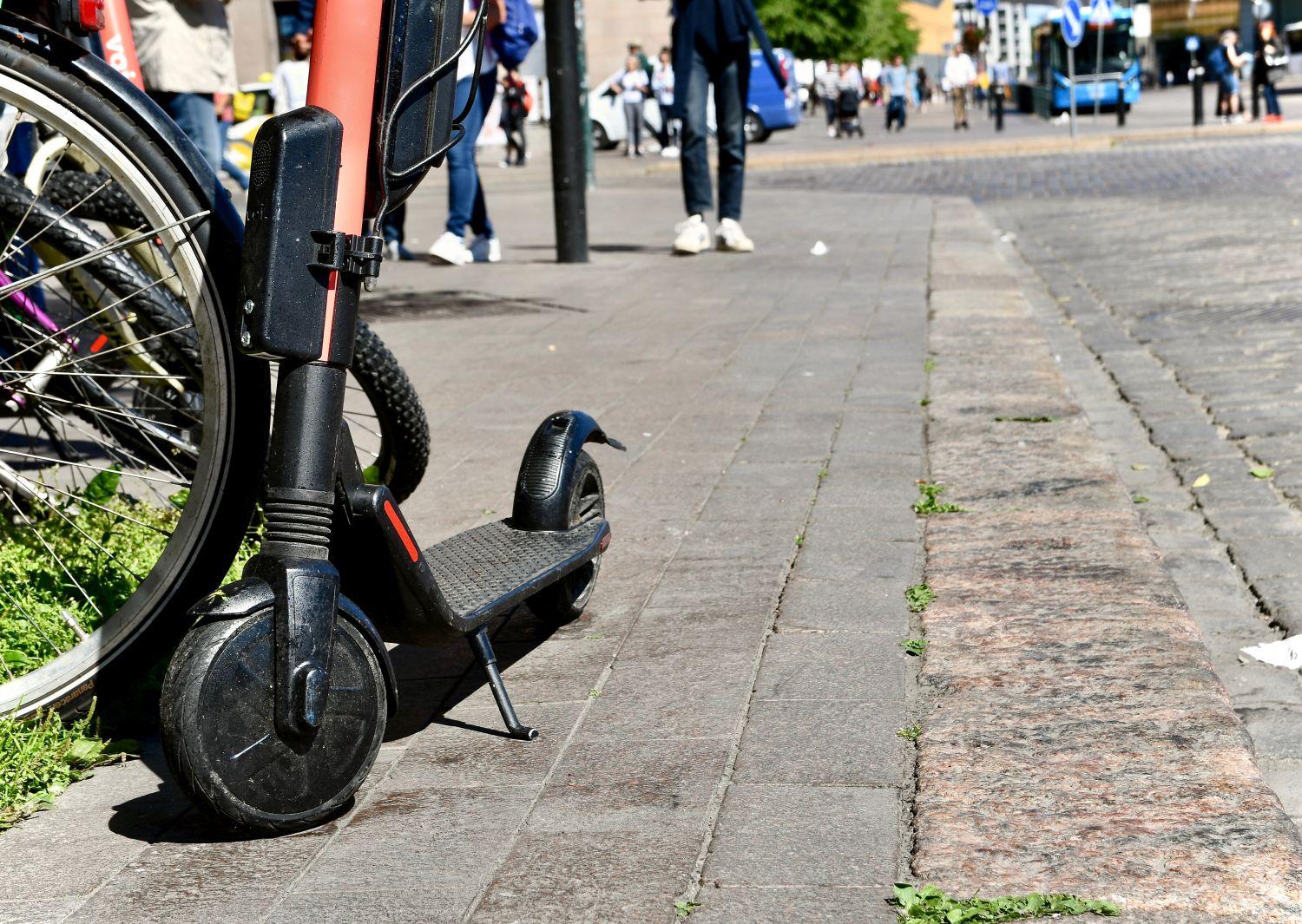 Elsparkcykel parkerad på trottoar.