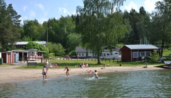 Lekande barn på sandstrand.