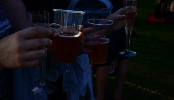 Ett par människor i skymning med ölstop och champagneglas i händerna.
