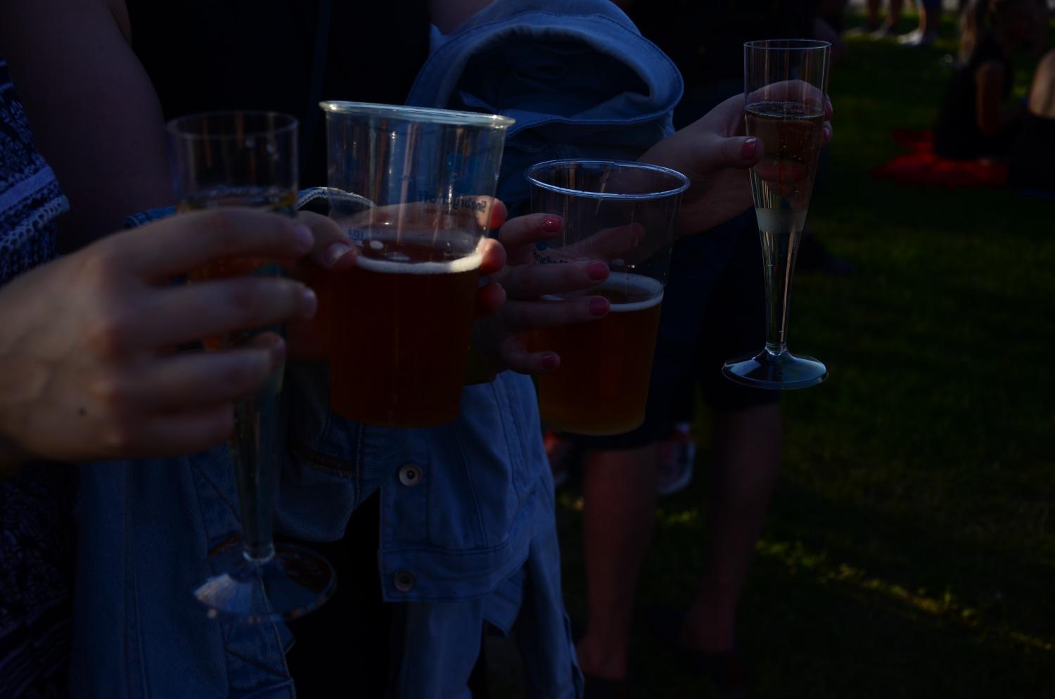 Ett par människor i skymning med ölstop och champagneglas i händerna.