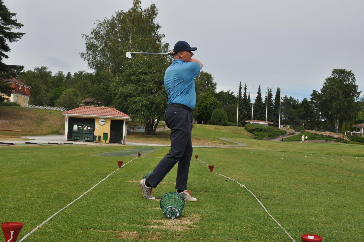 En golfare som övar på sin golfsving på en övningsgolfbana