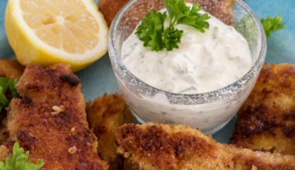 Fiskpinnar, en skål med sås och en citron.