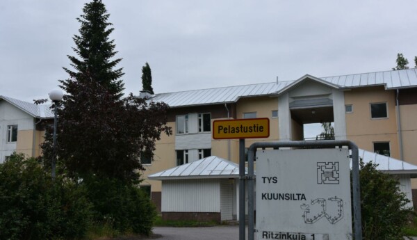 En skylt med en karta över Kuunsilta-bostadskomplexet och Studentbystiftelsens logotyp framför ett trevåningshus.