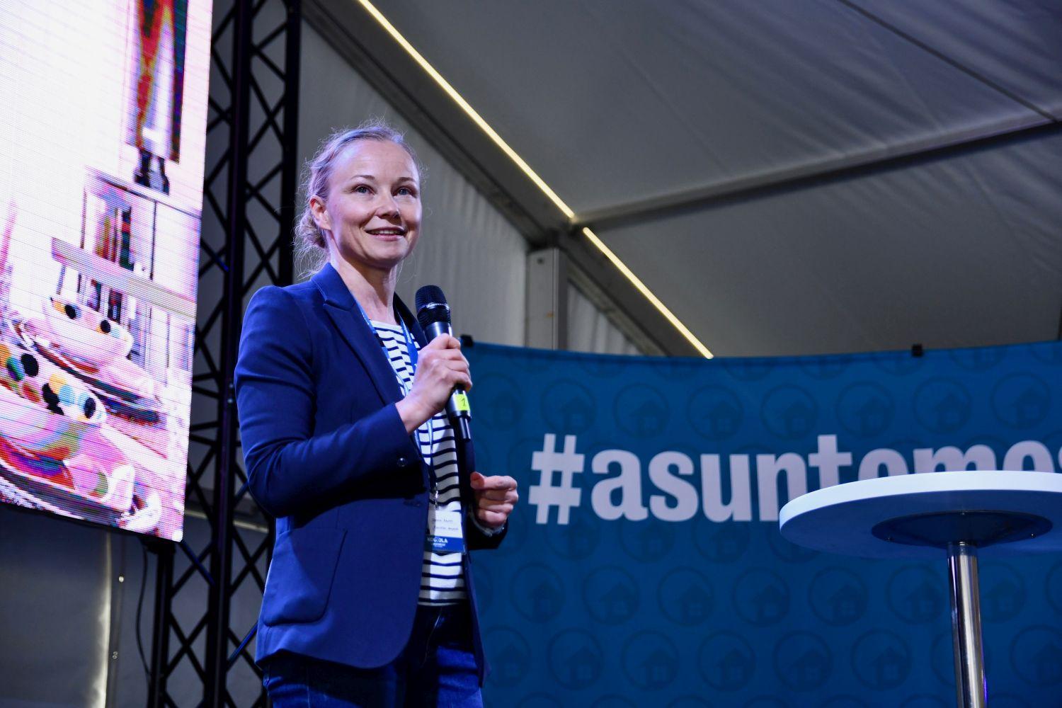 Sanna Kauppi talar i mikrofon på scen.