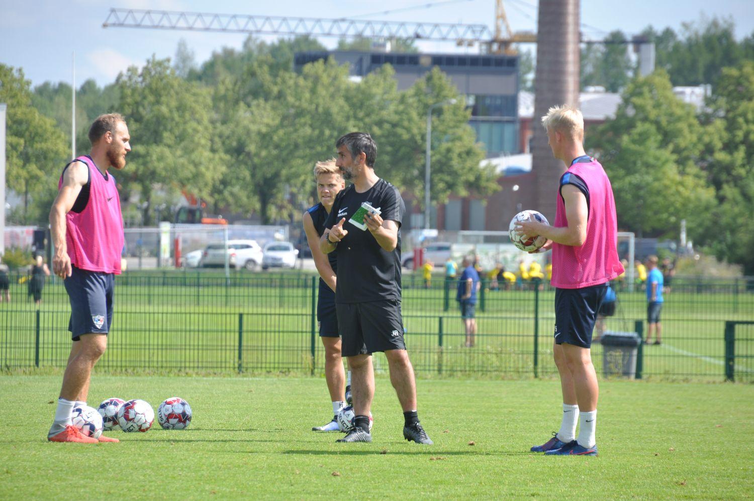 Tre fotbollsspelare får tips från sin tränare. 