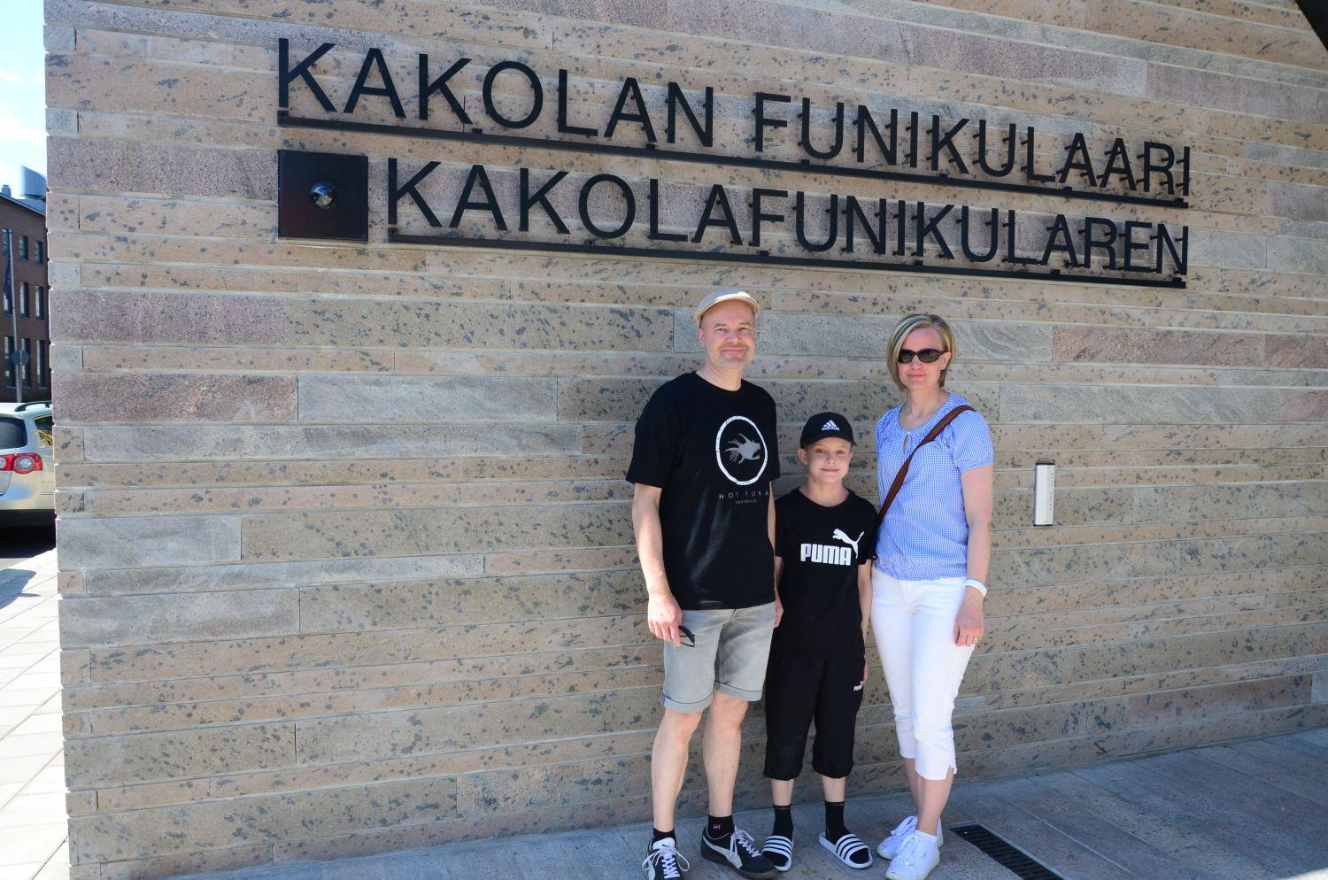 Paret Silvola med sonen Oliver står framför skylten med texten "Kakolafunikularen".