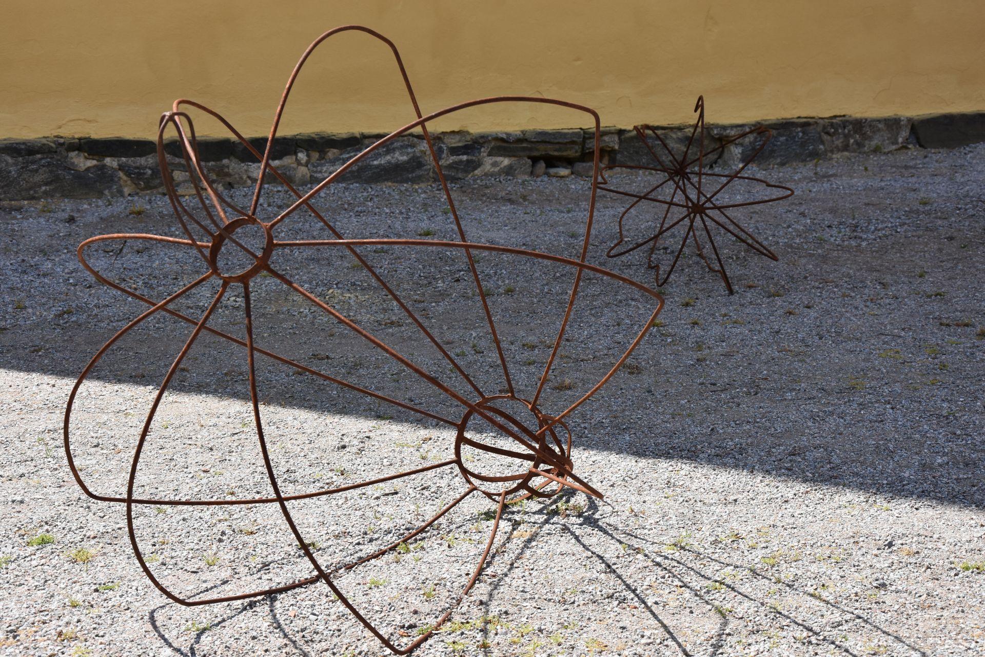 En abstrakt metallskulptur står placerad på en sandplan