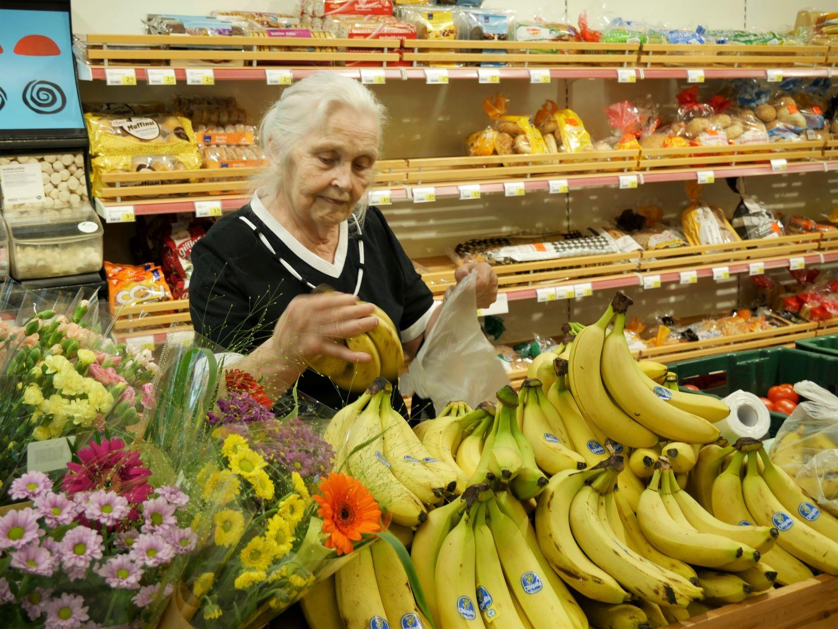 äldre kvinna handlar bananer i matbutiken