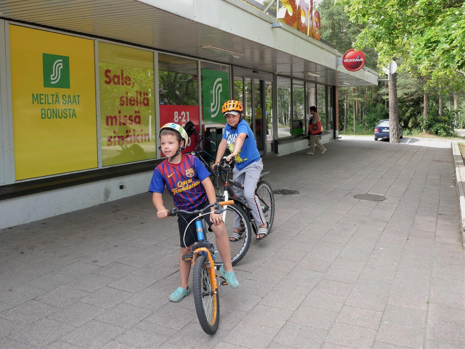 Två pojkar står på sin cykel utanför matbutik