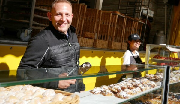 En man ler bakom en bakelsevitrin