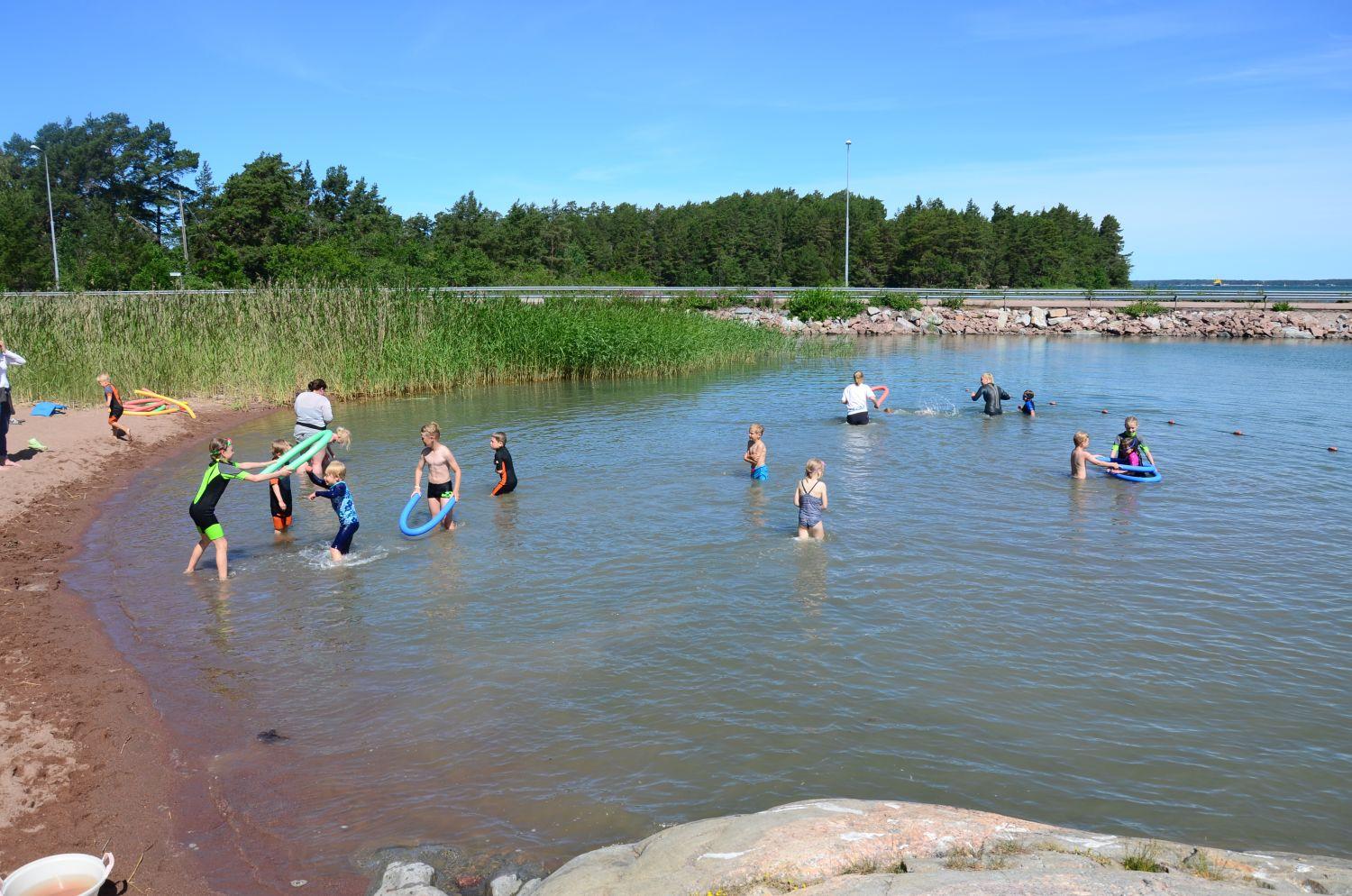 Ett tiotal barn plaskar runt i vattnet vid Kannvik badplats.