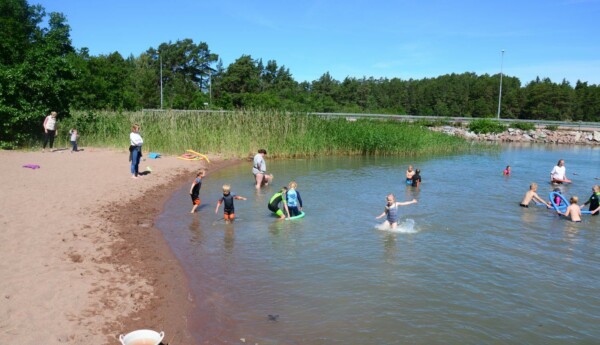 Ett tiotal barn plaskar runt i vattnet vid Kannvik badstrand.