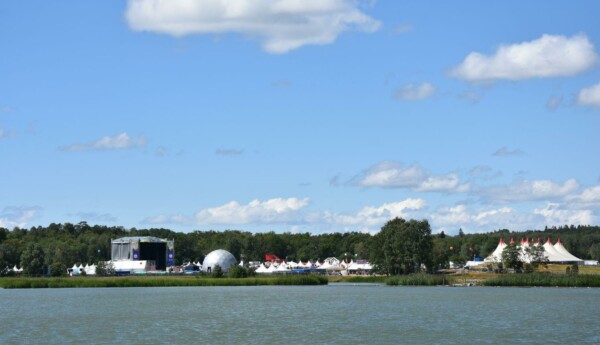 foto över området från vattnet. Man ser scener och byggnader. Solen lyser.