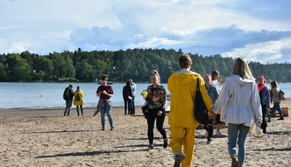 folk i regnkläder går längs en solig strand