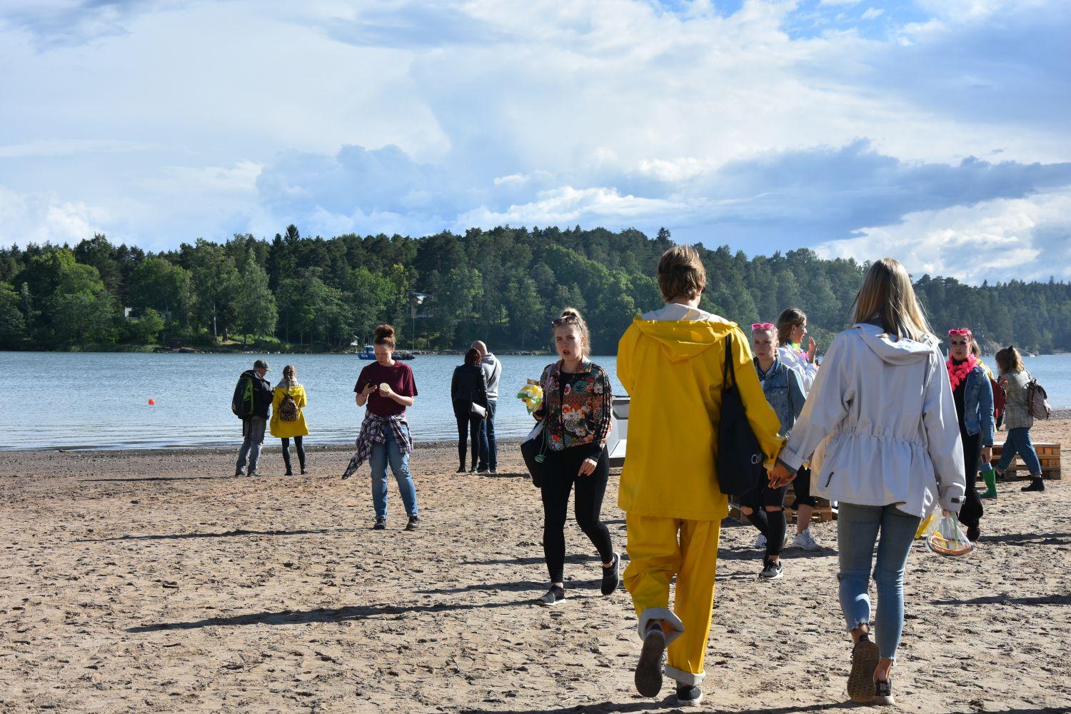 folk i regnkläder går längs en solig strand