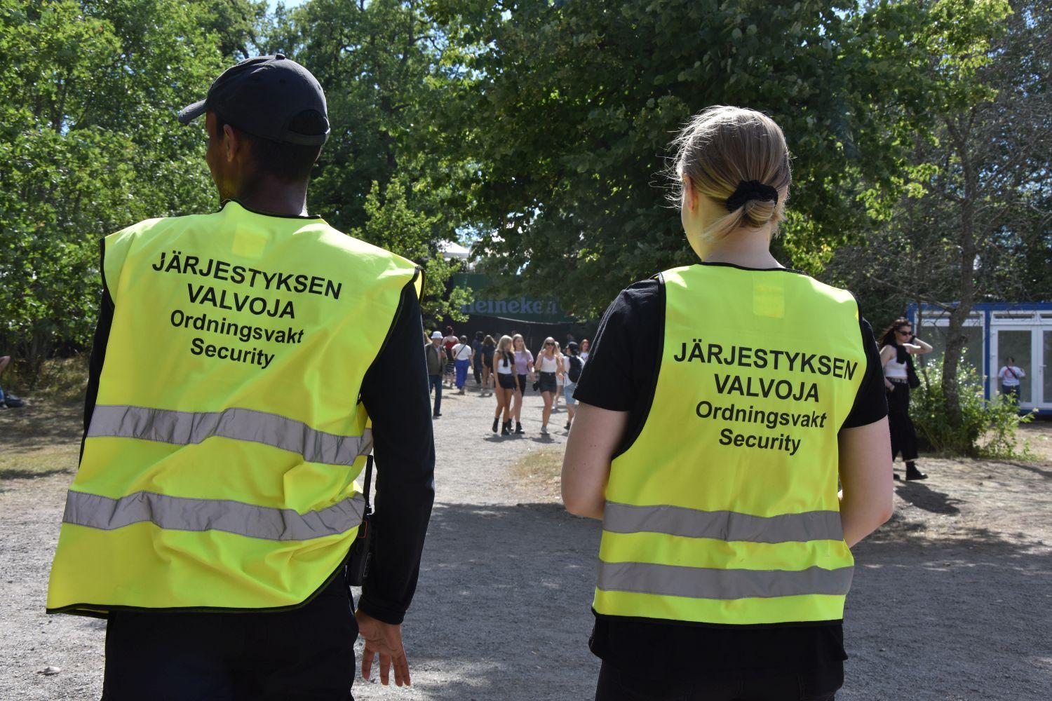ryggen av två säkerhetsvakter.Texten på ryggen säger säkerhetsvakt på finsk, svenska och engelska.