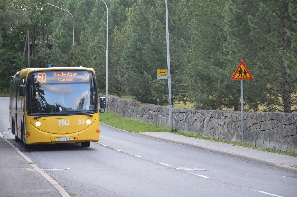 En buss med texten "50 Studentbyn Caribia"kör längs en väg.