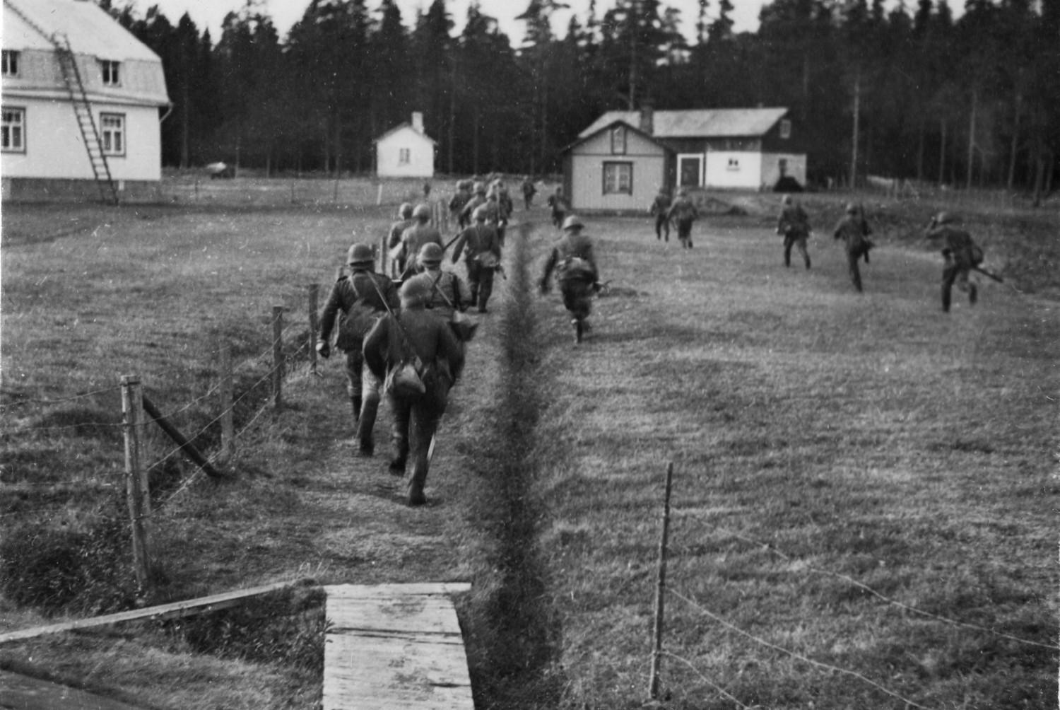 Soldater springer över äng.