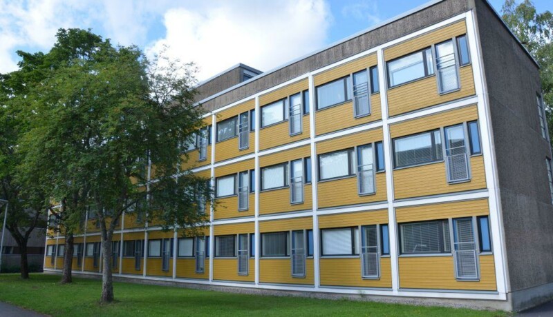 Ett höghus i betongfärg med gula väggar.