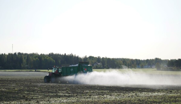 En traktor som sprider ut något på en åker.