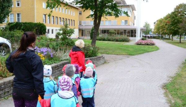 barn i ljusblå västar framför ett rappat gult stadshus