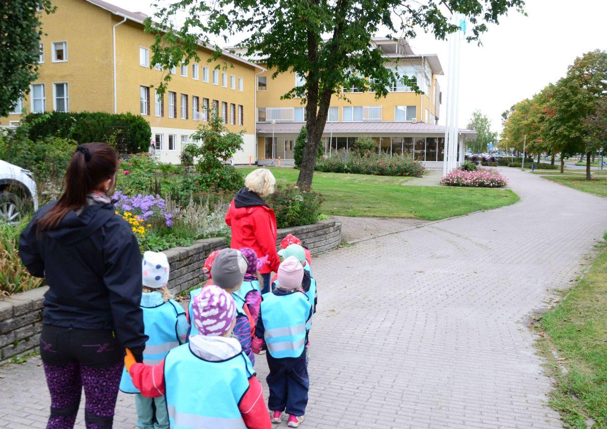 barn i ljusblå västar framför ett rappat gult stadshus