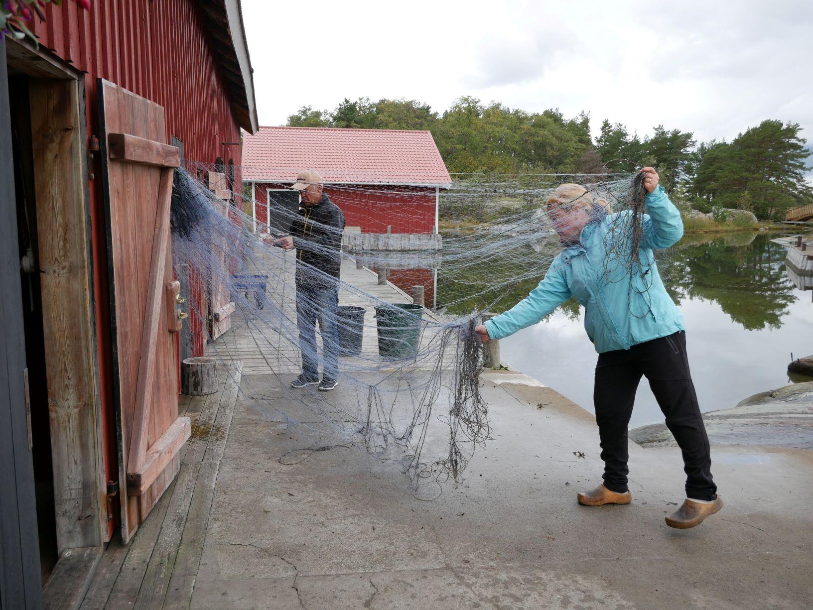 Två personer reder ut ett fisknät
