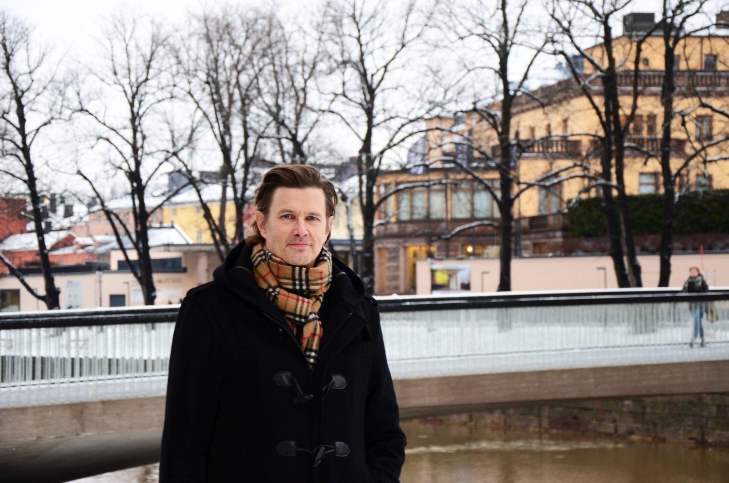 man med mörk rock och rutig halsduk utomhus