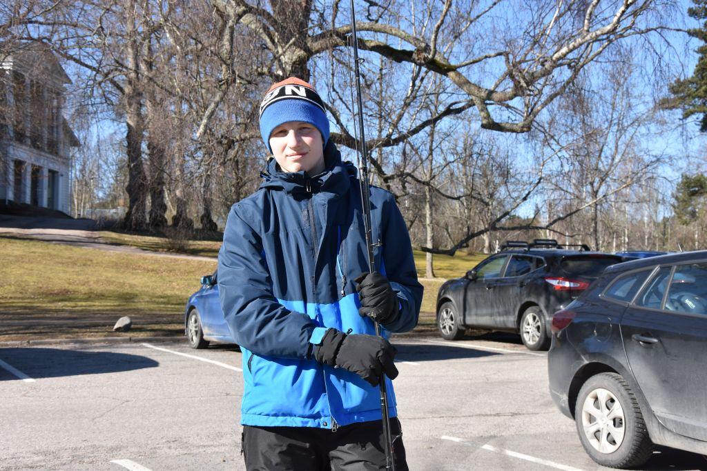 Vit pojke håller i fiskespö på parkeringsplats.