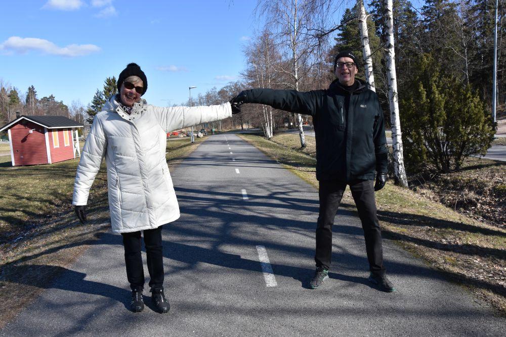 Ett äldre par står på två armlängdsavstånd från varandra och skrattar