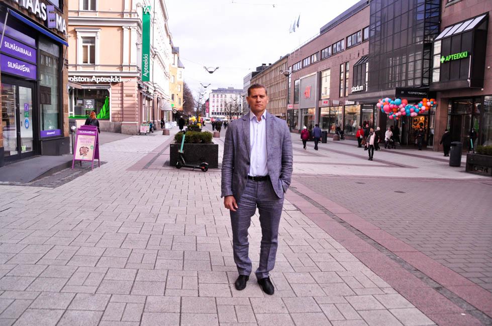 En man i grå kostym står på gågatan i Åbo.